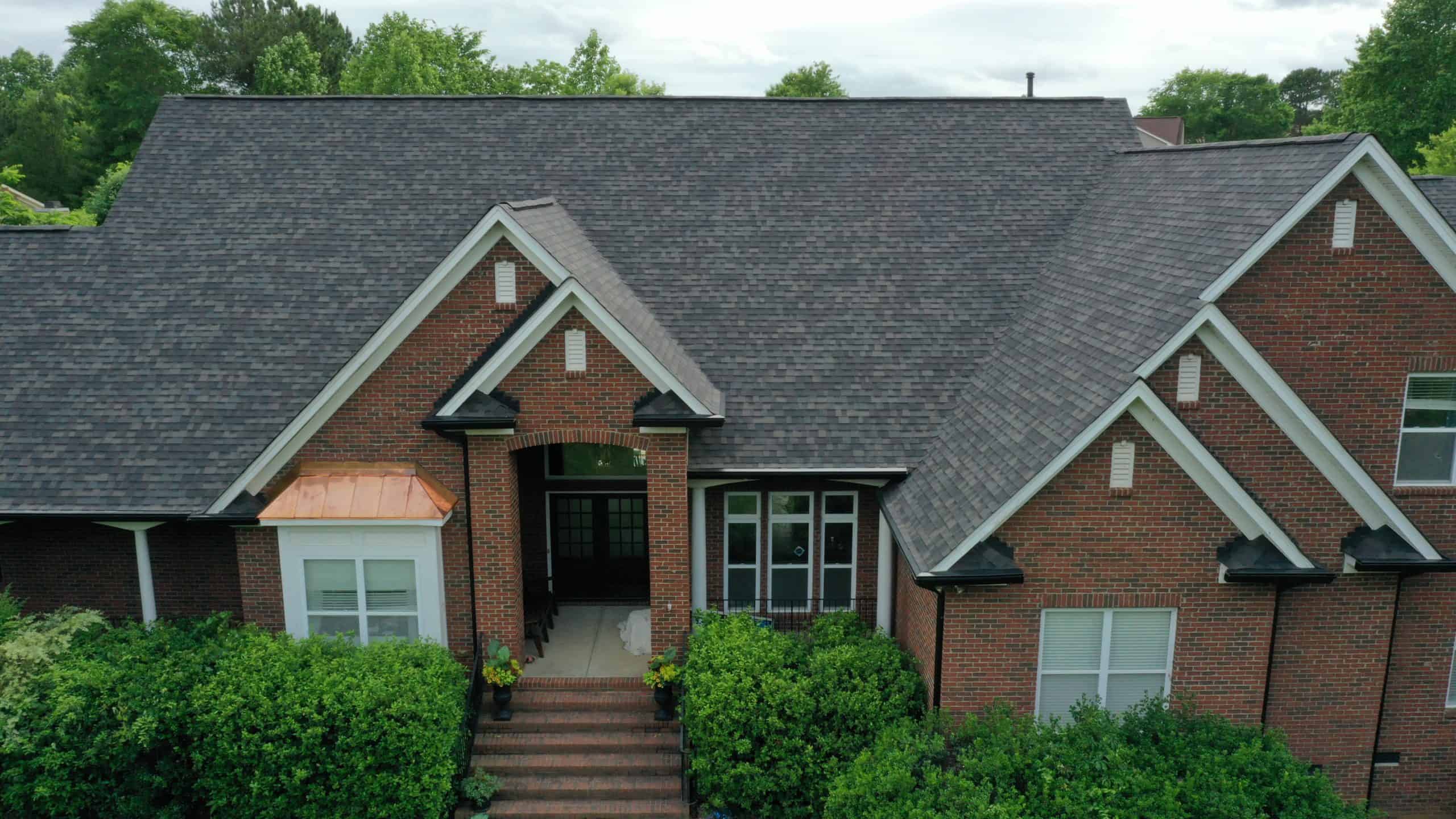 http://front%20view%20of%20brick%20home%20with%20black%20sable%20duration%20shingles%20and%20green%20bushes