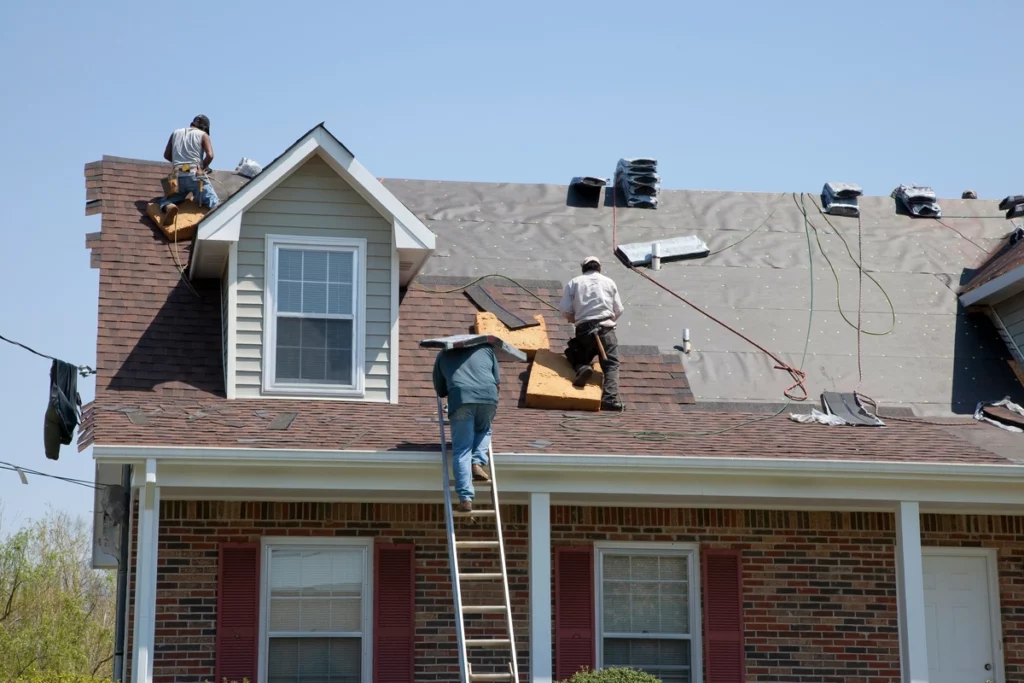 workers tarping a damaged roof