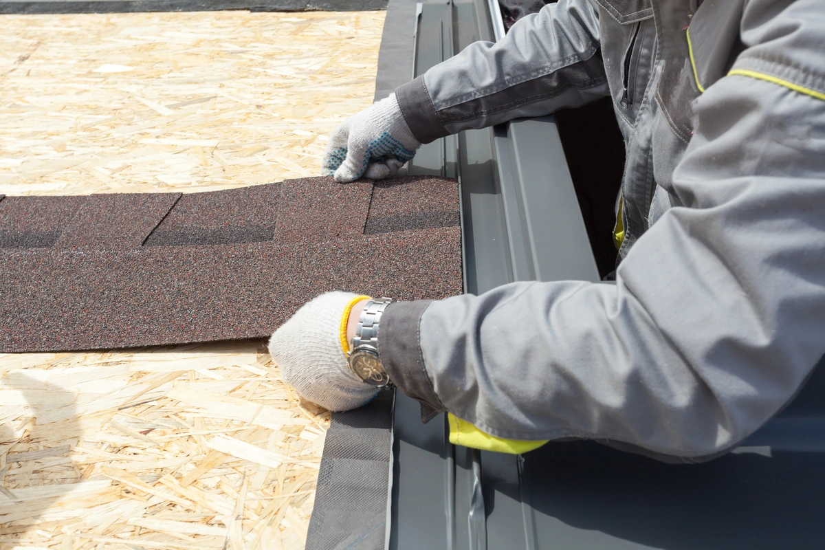 worker professionally placing asphalt tile sheet on the roof university city roofing