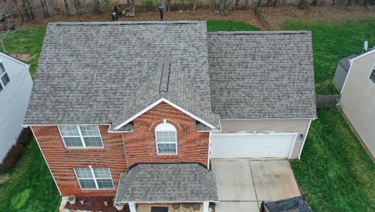 brick house with asphalt shingle roof and backyard