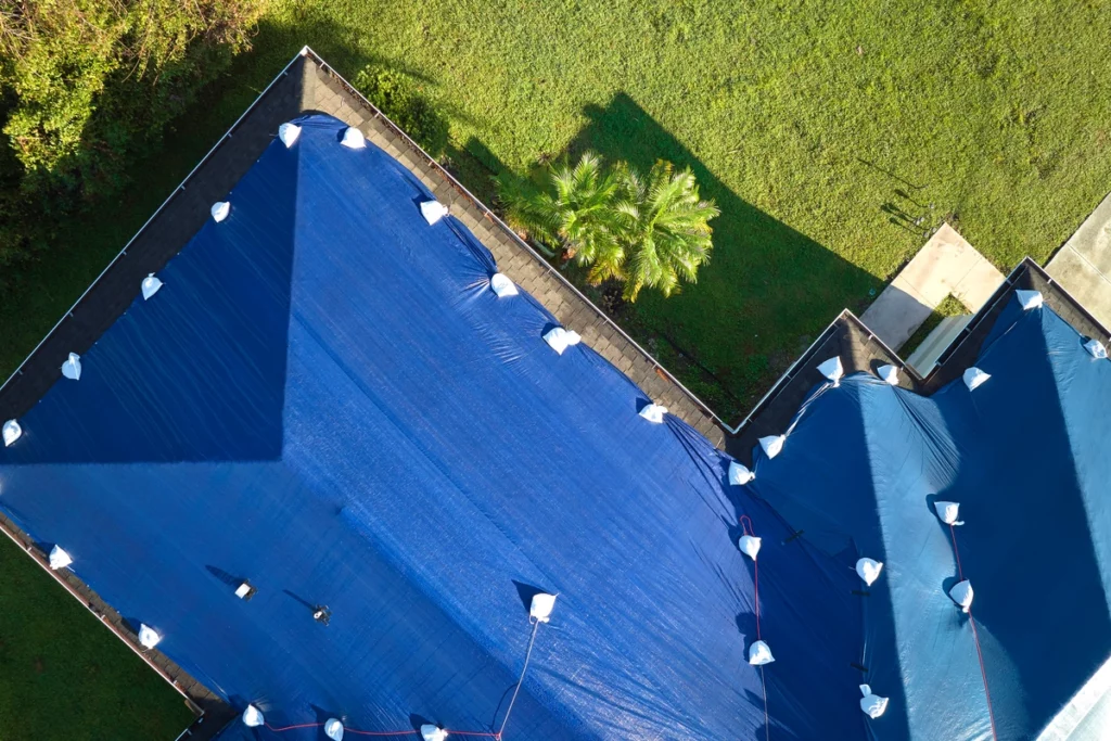 storm damaged house roof covered with tarp for protection