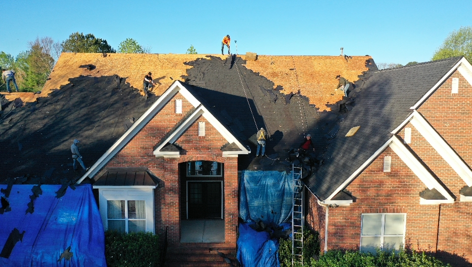construction workers in process of roof replacement of a brick house